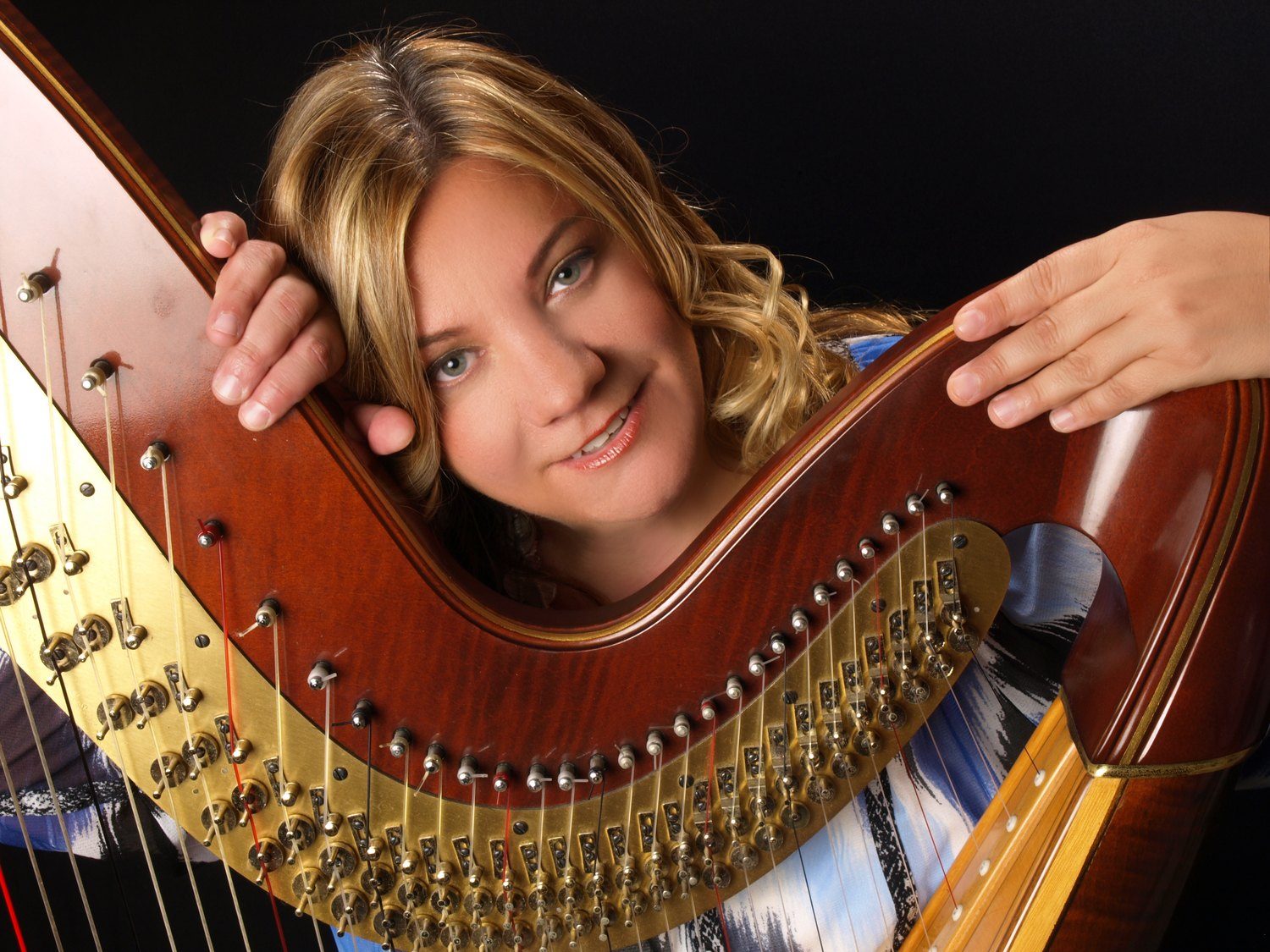 Patricia Turse resting against the neck of her harp