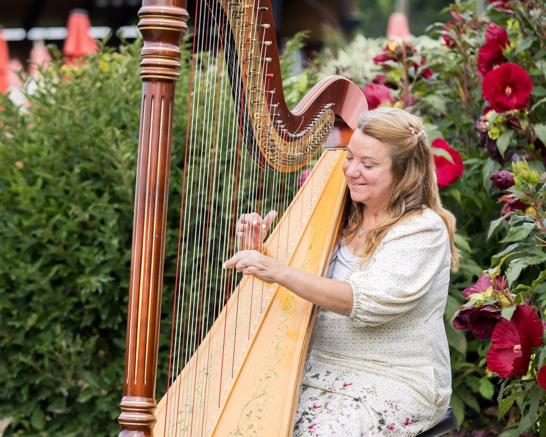 Patricia Turse seated, playing her full-size pedal harp